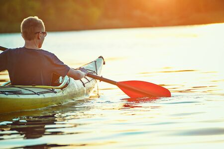 Kayaking couple ride along the river at sunsetの写真素材