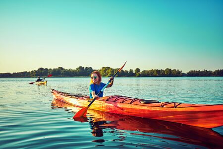 Kayaking couple ride along the river at sunsetの写真素材