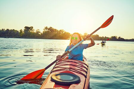 Kayaking couple ride along the river at sunsetの写真素材
