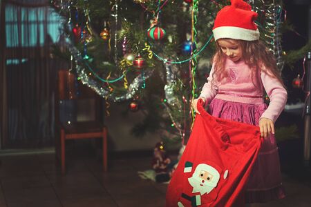 christmas, holidays and childhood concept - smiling child with gift box at homeの写真素材