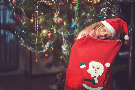 christmas, holidays and childhood concept - smiling child with gift box at homeの写真素材