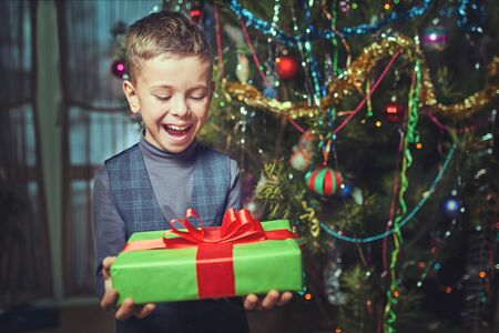 christmas, holidays and childhood concept - smiling child with gift box at homeの写真素材