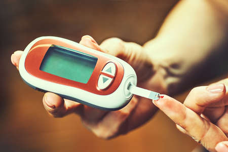 Close-up Of A Women's Hand Checking Blood Sugar Level With Glucometerの写真素材
