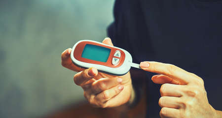 Close-up Of A Women's Hand Checking Blood Sugar Level With Glucometerの写真素材