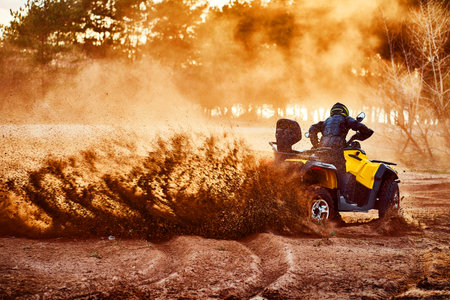 Teen riding ATV in sand dunes making a turn in the sandの写真素材