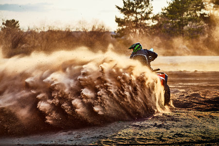 Teen riding ATV in sand dunes making a turn in the sandの写真素材