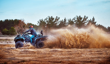 Teen riding ATV in sand dunes making a turn in the sand