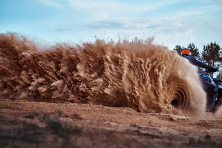 Teen riding ATV in sand dunes making a turn in the sand