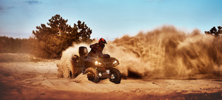 Teen riding ATV in sand dunes making a turn in the sandの写真素材