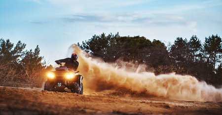 Teen riding ATV in sand dunes making a turn in the sandの写真素材