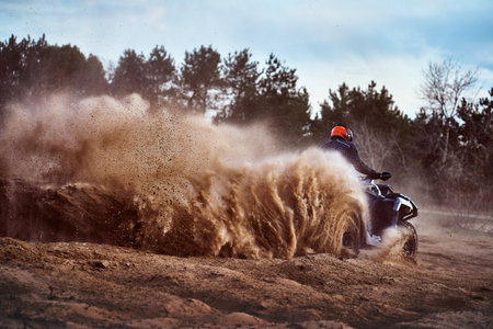Teen riding ATV in sand dunes making a turn in the sandの写真素材