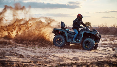 Teen riding ATV in sand dunes making a turn in the sandの写真素材