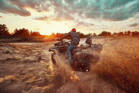 Teen riding ATV in sand dunes making a turn in the sandの写真素材