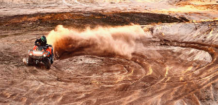 Teen riding ATV in sand dunes making a turn in the sand