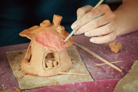 Children playing together with modeling clay and drawing by paints.