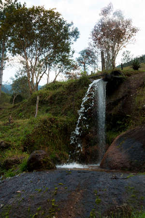 Waterfall with a large volume of water that flows through several rocks.の写真素材