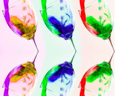 Colored liquid splash in a glass bowl. Effect in photography to show movement and give energy to the image. The photograph in question simulates a toast.の写真素材