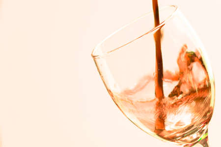 Colored liquid splash in a glass bowl. Effect in photography to show movement and give energy to the image. The photograph in question simulates a toast.の写真素材