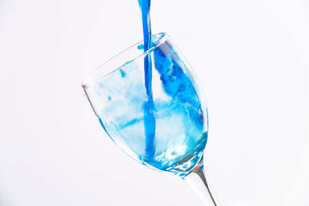 Colored liquid splash in a glass bowl. Effect in photography to show movement and give energy to the image. The photograph in question simulates a toast.の写真素材