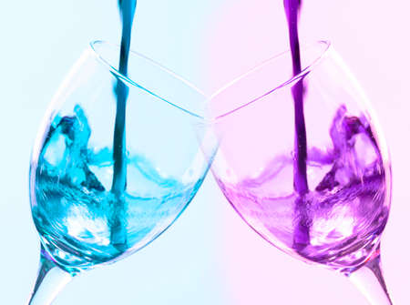 Colored liquid splash in a glass bowl. Effect in photography to show movement and give energy to the image. The photograph in question simulates a toast.の写真素材