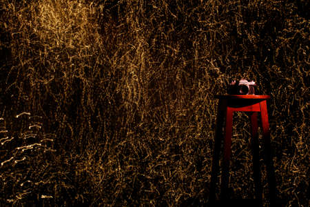 Photo camera on a wooden bench in a photo studio in the background with a trail of colored light.の写真素材