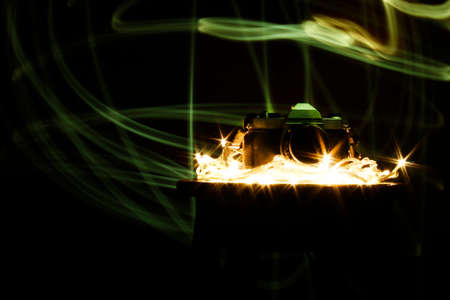 Photo camera on a wooden bench in a photo studio in the background with a trail of colored light.の写真素材