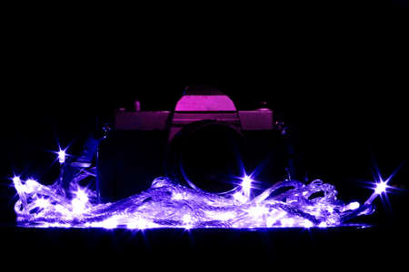 Photo camera on a wooden bench in a photo studio in the background with a trail of colored light.の写真素材
