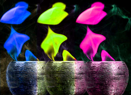 Water mixed with lighter fluid inside a golden pot throwing ice stone to cause thermal shock and cause a splash of liquid with fire on the black background.の写真素材