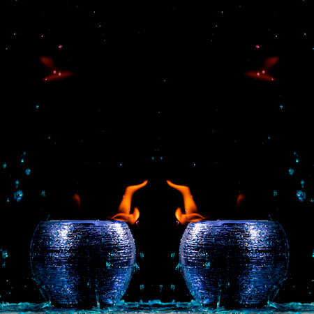 Water mixed with lighter fluid inside a golden pot throwing ice stone to cause thermal shock and cause a splash of liquid with fire on the black background.の写真素材