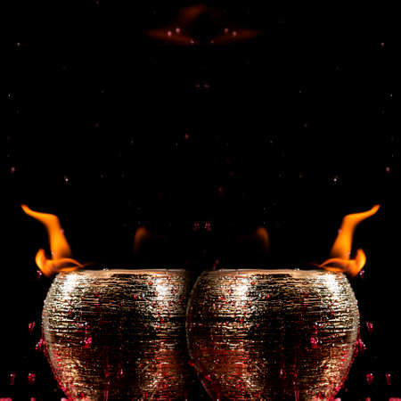 Water mixed with lighter fluid inside a golden pot throwing ice stone to cause thermal shock and cause a splash of liquid with fire on the black background.の写真素材