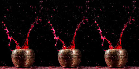 Water mixed with lighter fluid inside a golden pot throwing ice stone to cause thermal shock and cause a splash of liquid with fire on the black background.の写真素材
