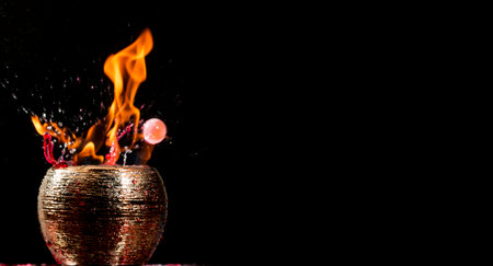 Water mixed with lighter fluid inside a golden pot throwing ice stone to cause thermal shock and cause a splash of liquid with fire on the black background.の写真素材