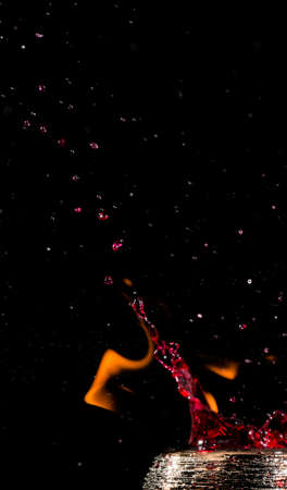 Water mixed with lighter fluid inside a golden pot throwing ice stone to cause thermal shock and cause a splash of liquid with fire on the black background.の写真素材