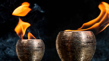 Water mixed with lighter fluid inside a golden pot throwing ice stone to cause thermal shock and cause a splash of liquid with fire on the black background.の写真素材