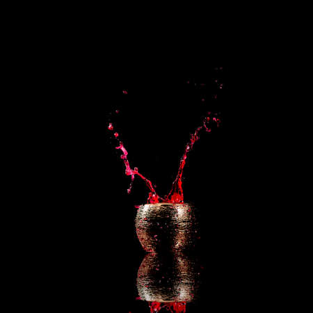 Water mixed with lighter fluid inside a golden pot throwing ice stone to cause thermal shock and cause a splash of liquid with fire on the black background.の写真素材