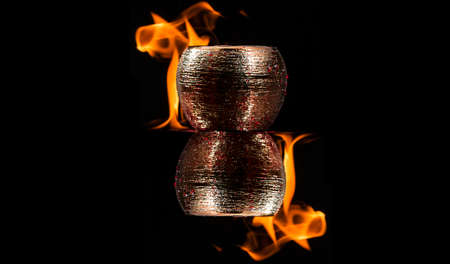 Water mixed with lighter fluid inside a golden pot throwing ice stone to cause thermal shock and cause a splash of liquid with fire on the black background.の写真素材