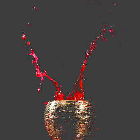 Water mixed with lighter fluid inside a golden pot throwing ice stone to cause thermal shock and cause a splash of liquid with fire on the black background.の写真素材
