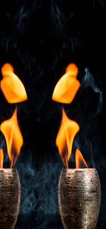 Water mixed with lighter fluid inside a golden pot throwing ice stone to cause thermal shock and cause a splash of liquid with fire on the black background.の写真素材