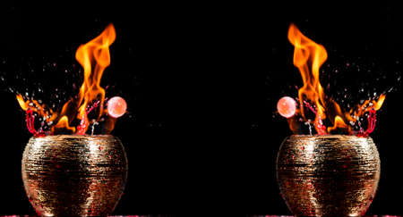 Water mixed with lighter fluid inside a golden pot throwing ice stone to cause thermal shock and cause a splash of liquid with fire on the black background.の写真素材