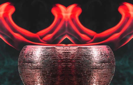 Water mixed with lighter fluid inside a golden pot throwing ice stone to cause thermal shock and cause a splash of liquid with fire on the black background.の写真素材