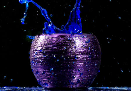 Water mixed with lighter fluid inside a golden pot throwing ice stone to cause thermal shock and cause a splash of liquid with fire on the black background.の写真素材