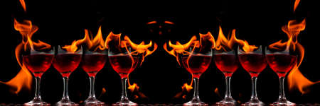 Colored liquid mixed with lighter fluid in a flaming cup where ice cubes are being placed to cause a...