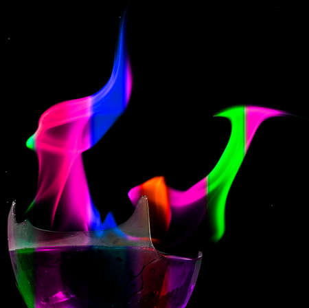 Colored liquid mixed with lighter fluid in a flaming cup where ice cubes are being placed to cause a thermal shock and generate an explosion.の写真素材