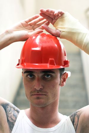 tattooed man with red helmet and hand in plaster