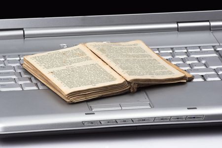 open old book over computer keyboard.