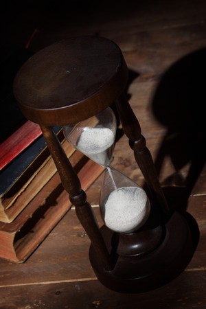 Hour- glass and old books close up
