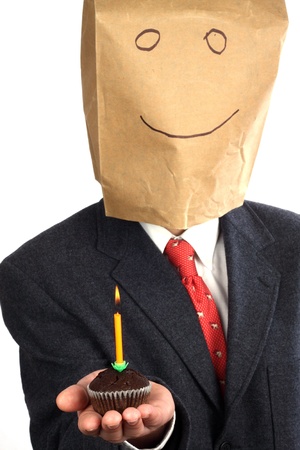 Businessman with paper bag on his head celebrating a birthday の写真素材