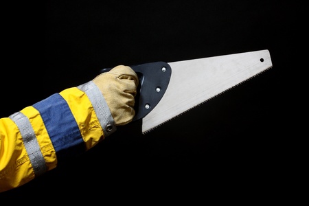 Worker holding a saw over black background の写真素材