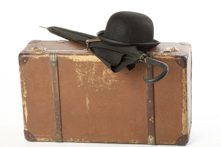 Old suitcase, bowler hat and umbrella over whiteの写真素材