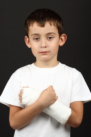 Boy with broken hand in cast, over blackの写真素材